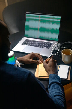 A man edits a script in a notebook before recording a podcast