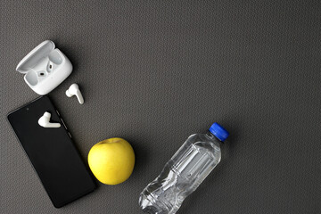 Naklejka premium Mat to exercise with the necessary objects such as wireless headphones, cell phone, apple, water to hydrate, sweat towel and locker keys 
