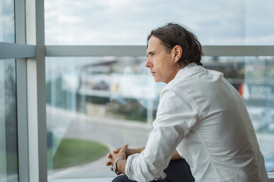 Thoughtful mature boss sitting near hotel window