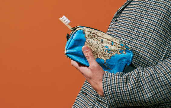 man carries a toilet bag patterned with a world map