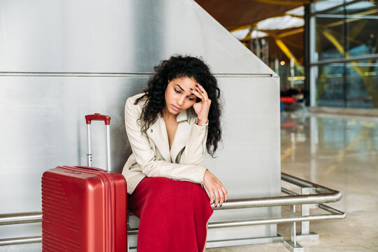 Upset woman sitting near luggage in airport