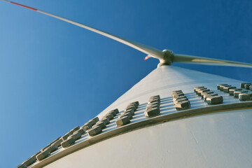 Bottom view of a windmill generating renewable energy against a blue sky on a beautiful spring day....