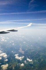 Fototapeta premium airplane wings in flight, with clouds and ground