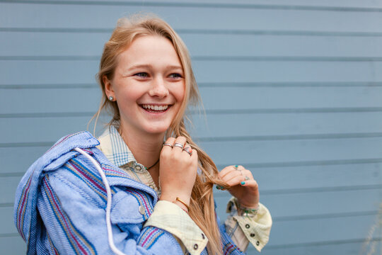 Happy blonde young woman braiding her hair
