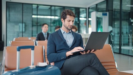 Handsome Indian or latin businessman sitting and working on laptop waiting for flight at airport terminal