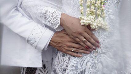 couple gently holding hands in bridal attire. bridal hands with elegant wedding rings with white gold diamonds. Bride's hands close-up of a ring. High quality photos.