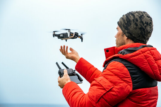 Male explorer operating drone near ocean