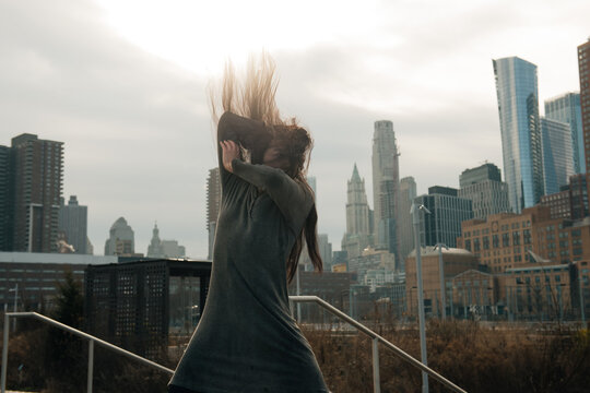 young female dancing wild in front of manhatan downtown skyline