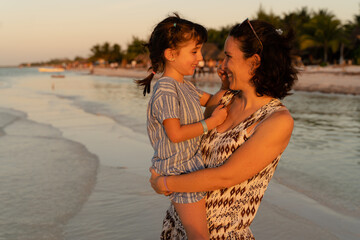 Fototapeta premium Happy woman holding daughter on beach