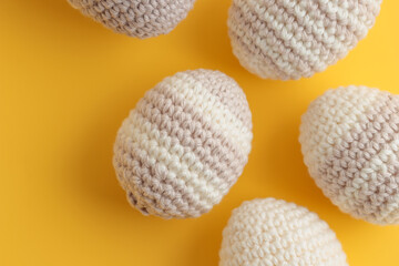 Set of cute striped pattern crocheted eggs, pastel color on a yellow