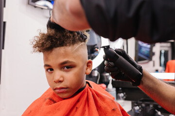 Mixed race boy with curly hair getting a fresh fade hair cut