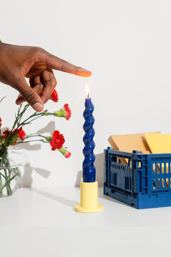 A black man touches a candle flame with his finger
