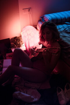 Inspired woman learning with small guitar in bedroom