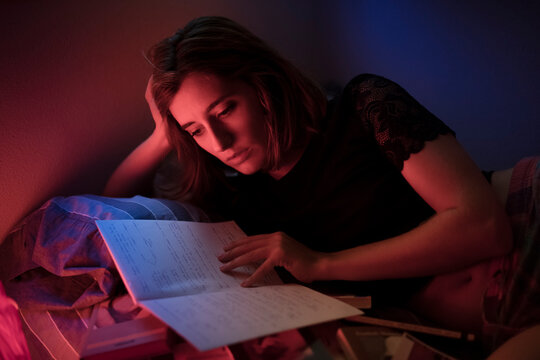 Student reading notes on bed with neon lighting 
