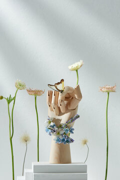 A butterfly lands on a hand among flowers in bright background