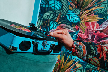 man putting a record in a blue portable turntable