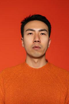 Stylish man against orange wall in studio