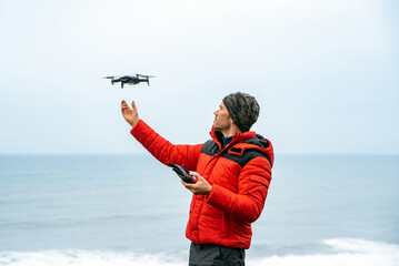 Naklejka premium Male explorer operating drone near ocean