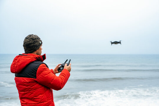 Male explorer operating drone near ocean