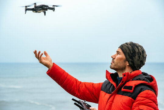 Male explorer operating drone near ocean