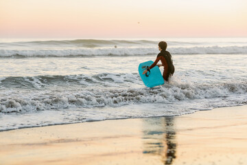 Teen boy enjoying surfing at the beach in California