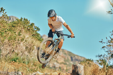 Cycling, jumping and man on bicycle in the countryside for fitness, stunt and freedom on blue sky...