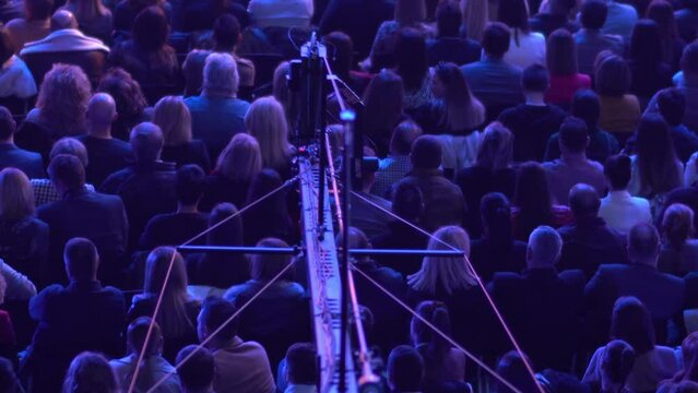 Video camera on the tap of eople on business conference. The movement of the camera over the audience under the ceiling. Shooting from a height.