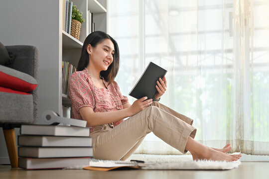 Bottom View Of Beautiful Woman Sitting Floor In Living Room And Reading A Book, Spending Leisure Weekend Time At Home