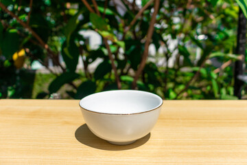 An empty bowl placed on a wooden board. Edited photo.