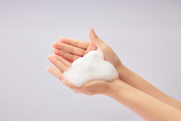 White cleanser foam texture placed on female hand model on a white background. Cleanser product...