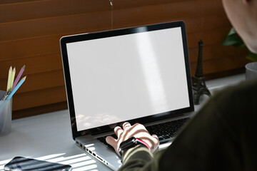 Over shoulder view of young man student using laptop computer at home. Distance study, work from...