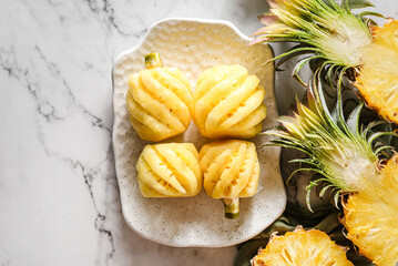 peeled small pineapple on a white plate