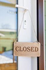 wooden sign is closed on door of restaurant or store. inscription with mode of operation on window of coffee shop. mass closure of public catering establishments, canteens.