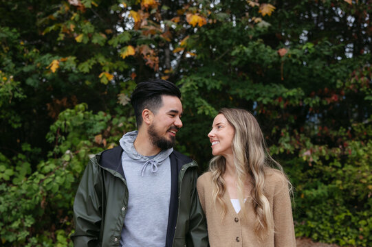 Fun couple standing together outside near trees.
