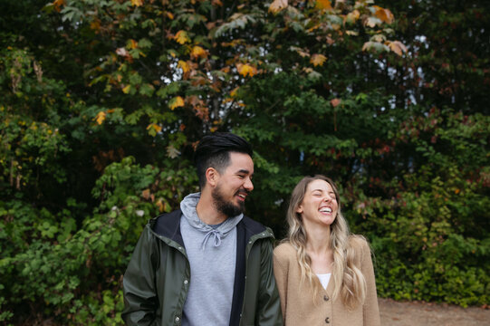 Fun couple standing together outside near trees.