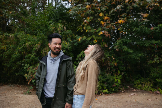Fun couple standing together outside near trees.