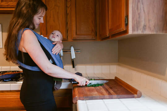 Mom cooking in kitchen while carrying her baby