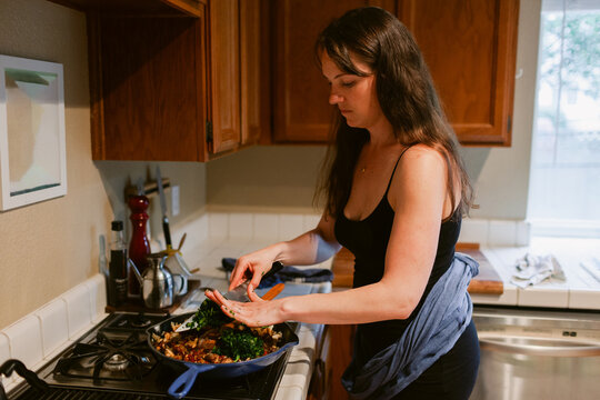 Woman with sling cooking in iron skillet pan on range