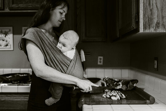 New mom cooking while carrying her baby in a sling 