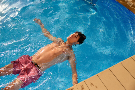 Young man floating in pool water