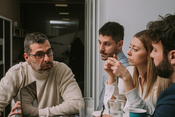 Inter-generational group of business people having a meeting at modern office late at night