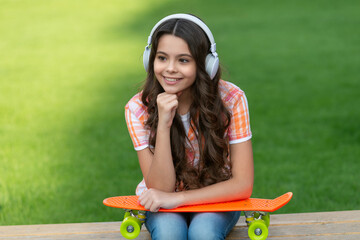 smiling teen girl with skateboard outside. photo of teen girl with skateboard listen music