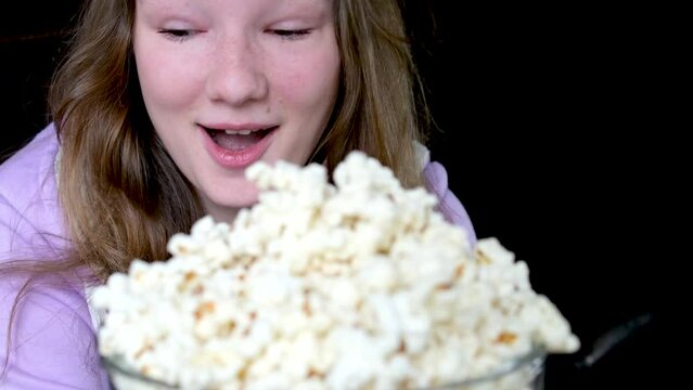 close-up slow motion video pouring a lot of popcorn scatters in different directions girl rejoices laughs looks at it, happy expression of a child of a young woman teenager smile sincere laughter