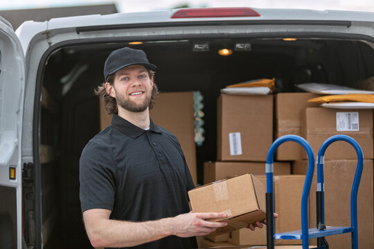Shipment: Smiling Delivery Man Puts Boxes On Dolly