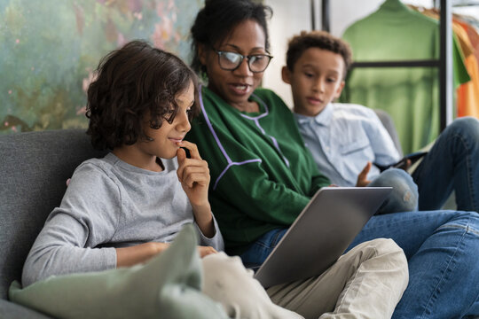 Black mother sitting with sons using gadgets