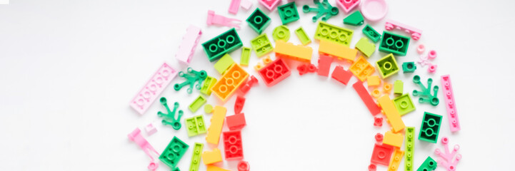 Top view on multicolor toy bricks on white wooden background. Children toys on the table.Developing...