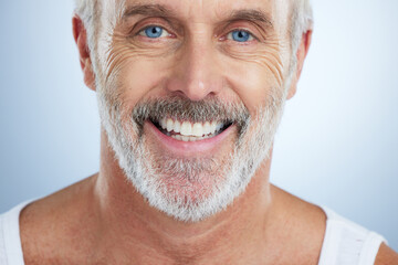 Senior man, face and teeth with smile for dental care, hygiene or surgery against a studio...