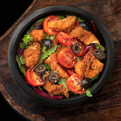Healthy green salad with crispy fried breaded chicken breast strips and tomatoes