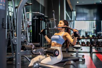 Asian woman fitness exercises at gym lat pulldown machine, Making an effort and training hard for fit body, Healthcare, Firm exercise, healthy fit and Sport concept.