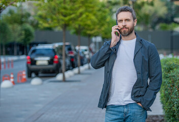 man has mobile call outdoor, copy space. man having mobile call in the street.